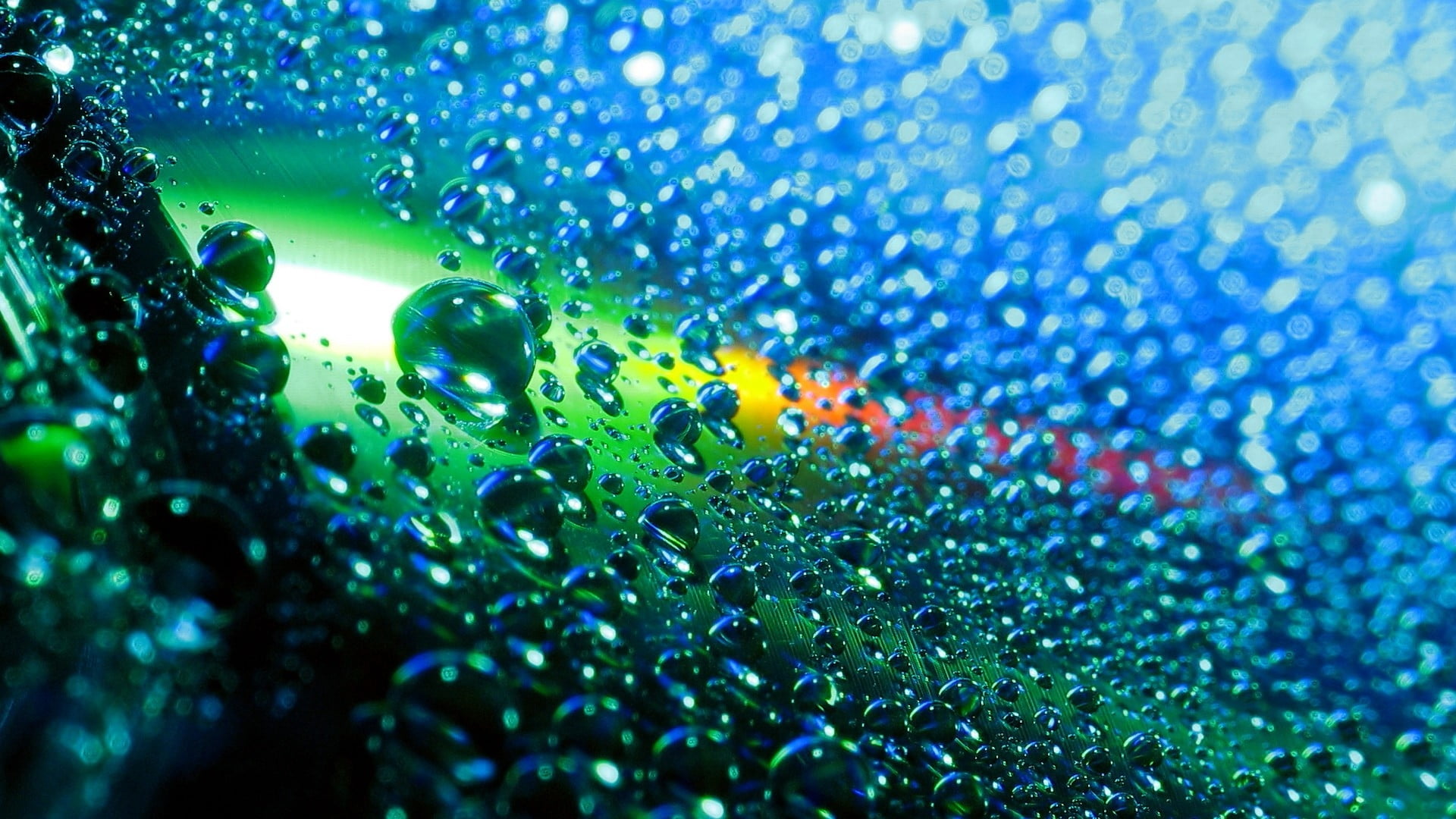 macro photography of water droplets with green and blue lights