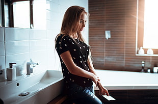 woman wearing black top leaning on sink