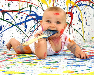 baby in white onesie  covered with paint