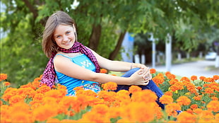 girl in blue camisole sitting on orange Marigold flower field at daytime