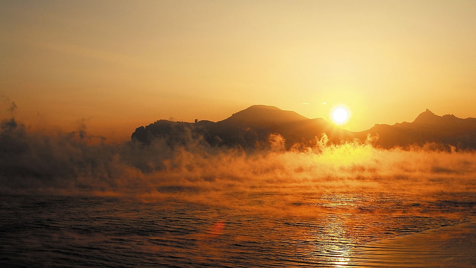 body of water with evaporating smokes during golden hour HD wallpaper