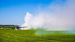green grass field, airplane, smoke