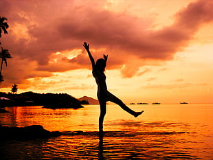 silhouette photo of woman standing on calm body of water