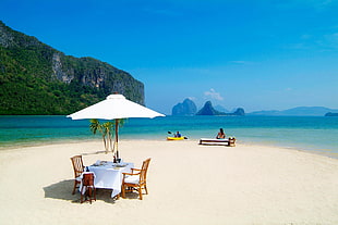 Woman sitting on bench in the middle of beach during day time