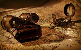 brown binocular and compass on world map