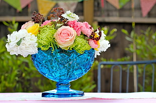 pink, white, and green petaled flowers bouquet with blue translucent vase close-up photography