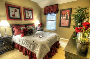 vacant red and white platform bed with comforter set beside wooden nightstand with table lamp
