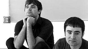 grayscale photo of two men sitting beside each other