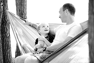 grayscale photo of man and boy on hammock