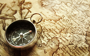 gray navigation compass on brown map