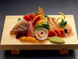 assorted sushi sashimi and wasabe meal served on brown wooden tray
