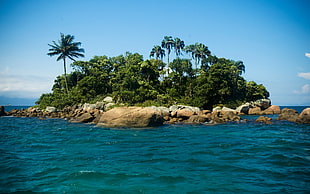 island surround by body of water and rocks under blue sky
