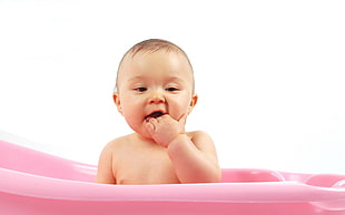 baby inside plastic bather holding his mouth