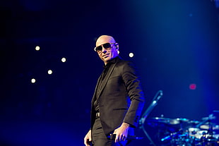 man in black suit standing on stage
