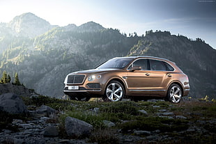 brown Bentley SUV on dirt road near mountain at daytime