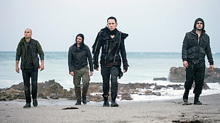four man walking on sea shore