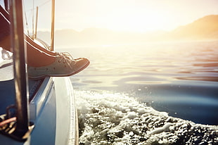 woman wearing blue boat shoes sitting on white boat