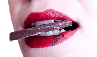 woman in red lipstick biting chocolate