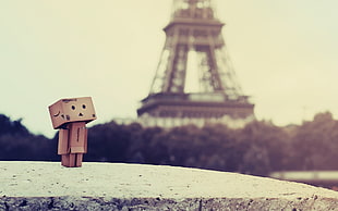 brown cardboard box cartoon character standing beside tower during daytime HD wallpaper