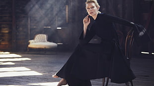 woman wearing black coat sitting on brown wooden chair