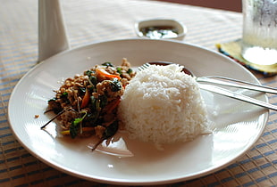 rice with ground meats on white ceramic plate with fork and spoon