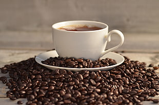 coffee beans and cup on saucer between coffee beans on table HD wallpaper
