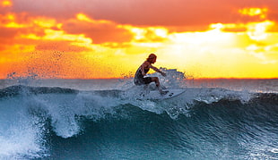 woman on white surfboard surfing during golden hours photography
