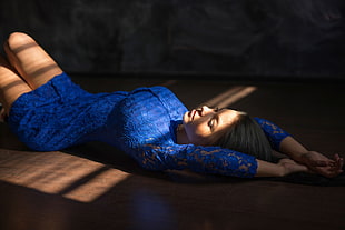 woman in blue dress lying on brown wooden surface