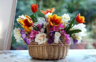orange, white, purple, and pink flowers in brown wicker basket
