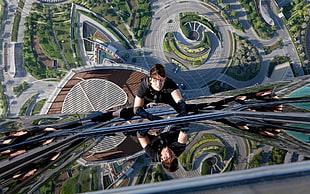 man in black shirt climbing high-rise building at daytime