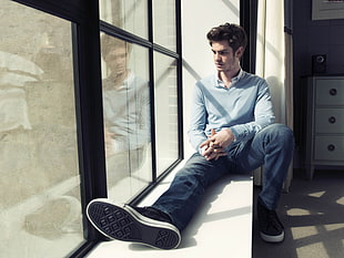 man in gray sweater and blue faded jeans sitting on white wooden side table during daytime HD wallpaper
