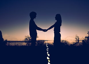 silhouette photo of man and woman holding hands