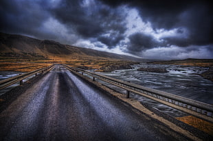 landscape photo of road with cloudy sky