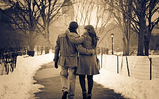 couple holding each other on road between snow floor sepia tone photography