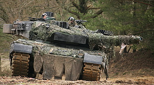 military tank covered with green camouflage net with soldier inside