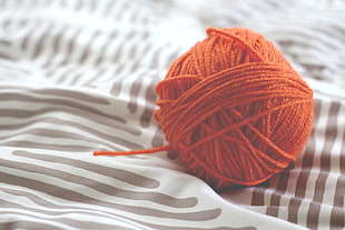 ball of orange yarn on textile HD wallpaper