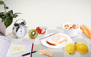 bread on white plate beside kitchen knife near of fruits and alarm clock