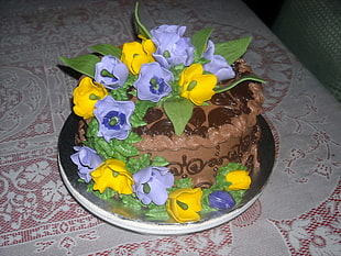 photo of brown cake with yellow and blue flower