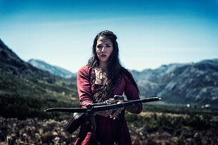 woman wearing red long-sleeved top holding black crossbow