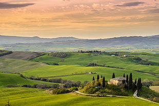photo of yellow and brown concrete house surrounded with green trees and field of green grasses, val d'orcia