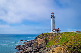photography of white lighthouse near mountain beside seashore under cloudy sky during daytime, pigeon point