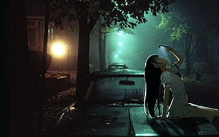 woman sitting on car during night