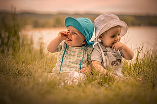 two baby's white and green hats, photography, baby, finger in mouth, grass