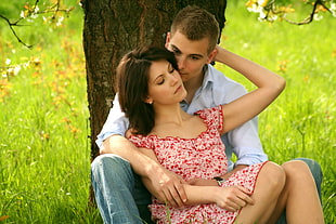 couple sitting under tree beside green grass