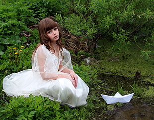 girl in white dress at grasses with boat origami