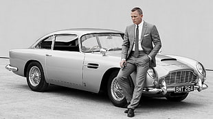 man wearing suit jacket sitting beside classic coupe