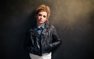 woman in black leather jacket standing near wall