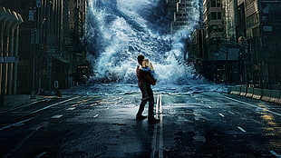 man carrying girl in front of big waves coming