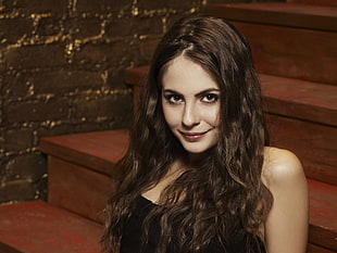 woman wearing black top on brown stair smiling