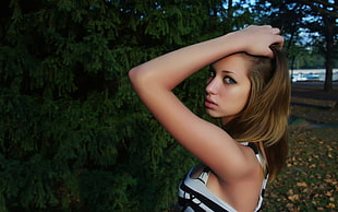 woman wearing sleeveless top holding head with left hand
